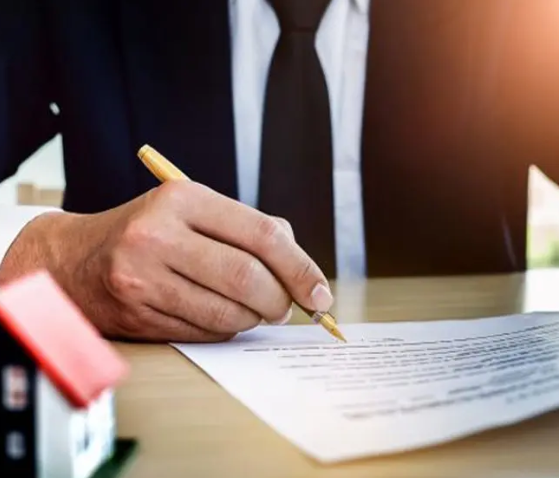 A person in a suit and tie writing on paper.