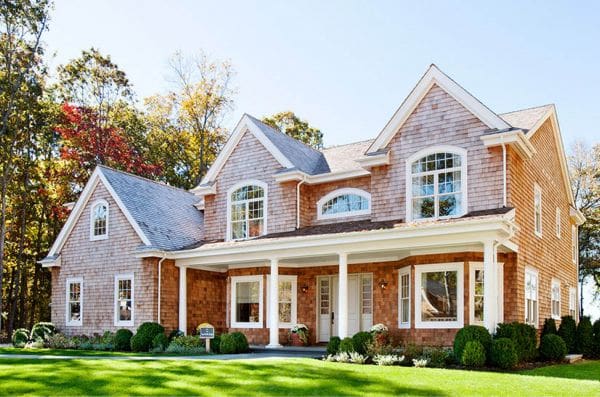 A large brick house with a porch and lawn.